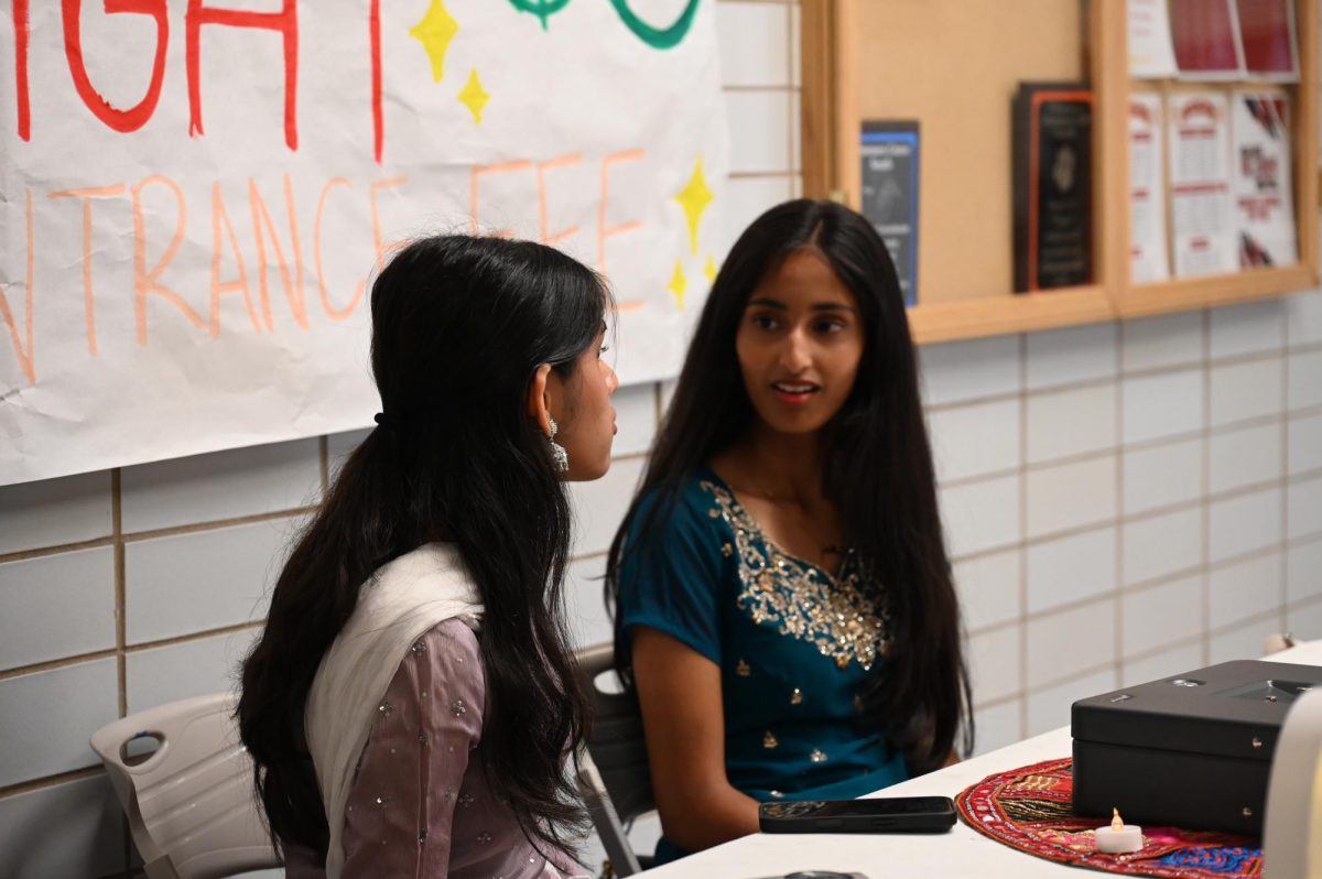 Seleena Matthew, senior, and Anam Hussaini, sophomore, welcome guests outside the contest gym. "I believe Garba Night went extremely well, and it turned out to be a successful and fun event for both our SASA board and the Niles North SASA board as well,"  Hussaini said.