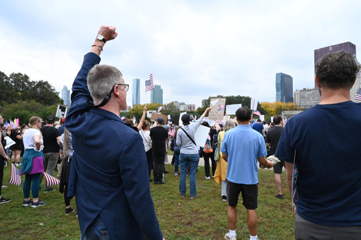 A man raises his fist in solidarity as guest speaker, Illinois governor J. B. Pritzker takes the stage for a speech. 