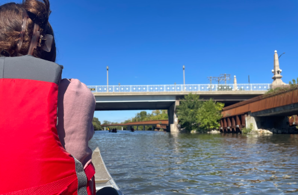 The view of the Chicago River from the middle seat of a canoe. 