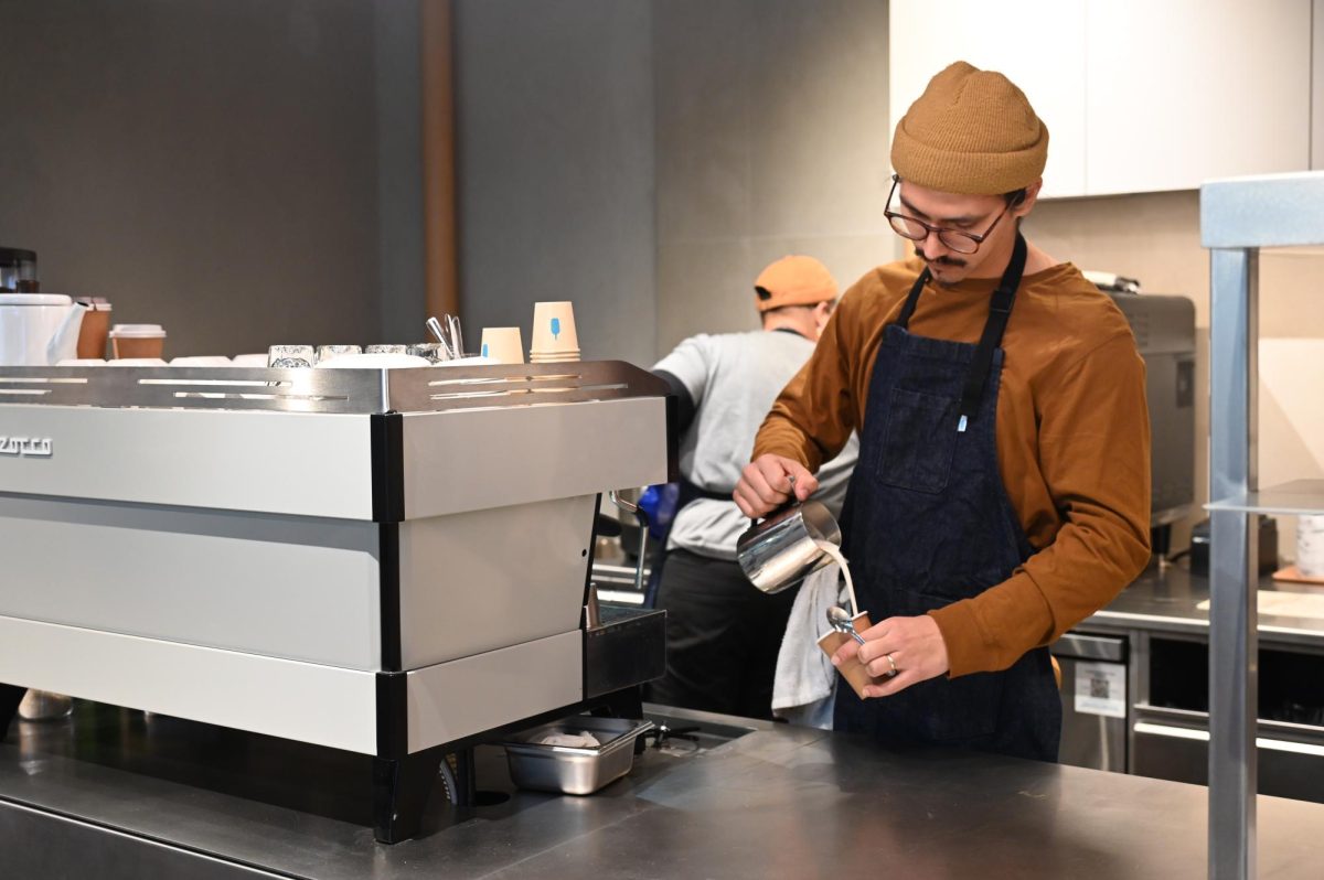 A Blue Bottle barista prepares a drink behind the counter, highlighting the craft and care behind each cup.