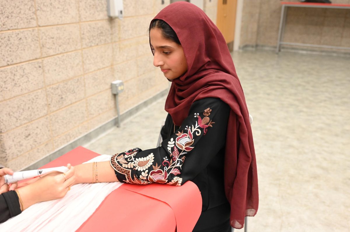 A student gets her hand designed by the henna booth.