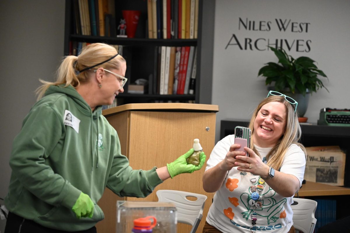 Deb Krohn shows a frog wearing a mini hat to the school librarian Vicki Pietrus.
