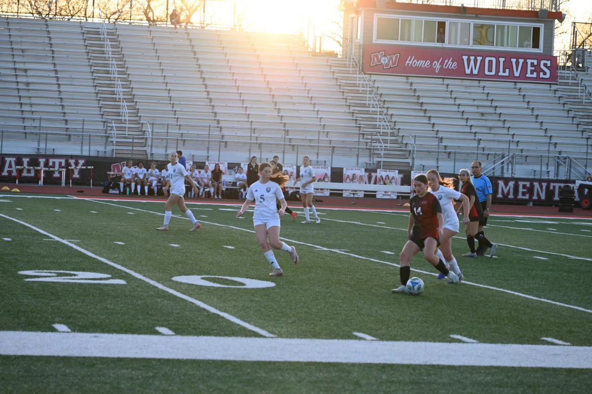 Vivienne Howard-Check, freshman, dribbles the ball away from Vernon Hills players. The team faced Vernon Hills on April 21., marking the start of conference games.