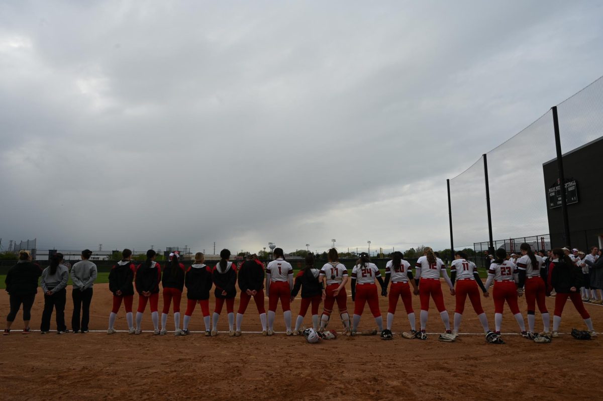 The girls varsity softball team lines up for the national anthem before their game on May 1.